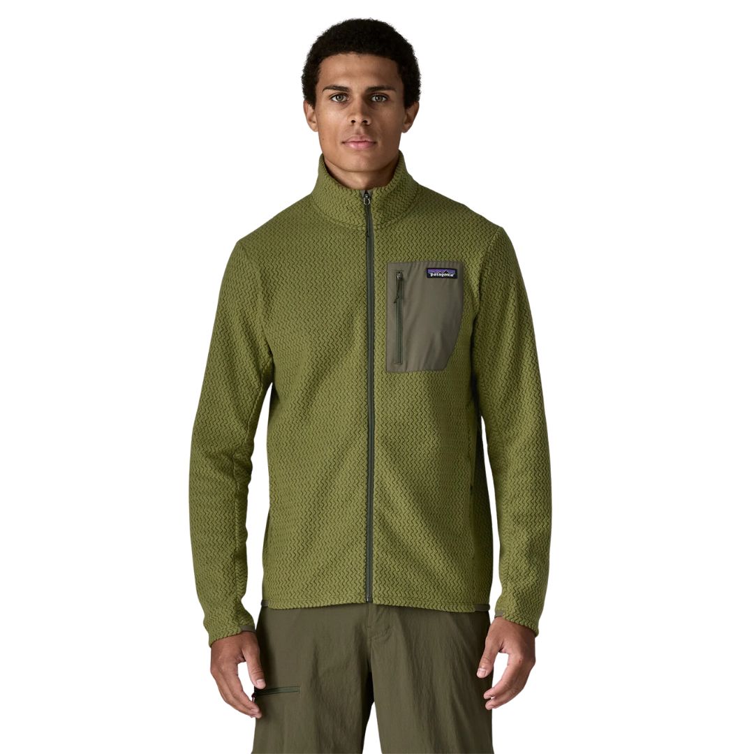 Patagonia Men's R1 Air Fleece Jacket en color caper green, vista frontal con modelo, cremallera completa cerrada, cuello alto, bolsillo pectoral izquierdo con panel en tejido liso verde oliva, cremallera con tirador y etiqueta Patagonia visible.
