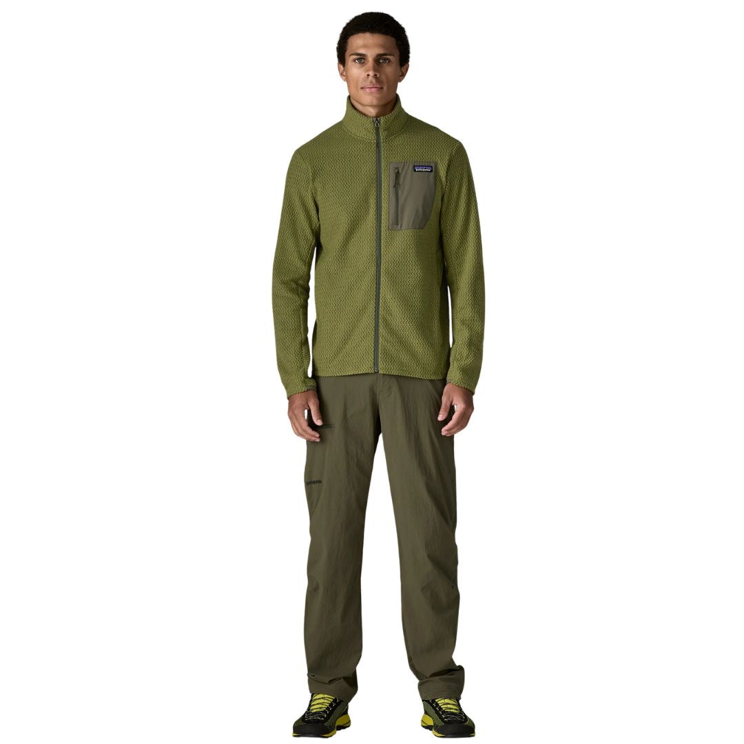 Patagonia Men's R1 Air Fleece Jacket en color caper green, vista frontal completa con modelo en look outdoor, combinada con pantalón técnico verde oscuro y zapatillas de aproximación.