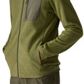 Patagonia Men's R1 Air Fleece Jacket en color caper green, detalle lateral del bajo con modelo usando el bolsillo delantero con cremallera minimalista, tejido jacquard en zigzag y ribete tejido en el bajo.
