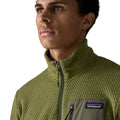 Patagonia Men's R1 Air Fleece Jacket en color caper green, detalle del cuello alto y cremallera completa con tirador, tejido jacquard en zigzag y bolsillo pectoral con panel liso verde oliva y etiqueta Patagonia.