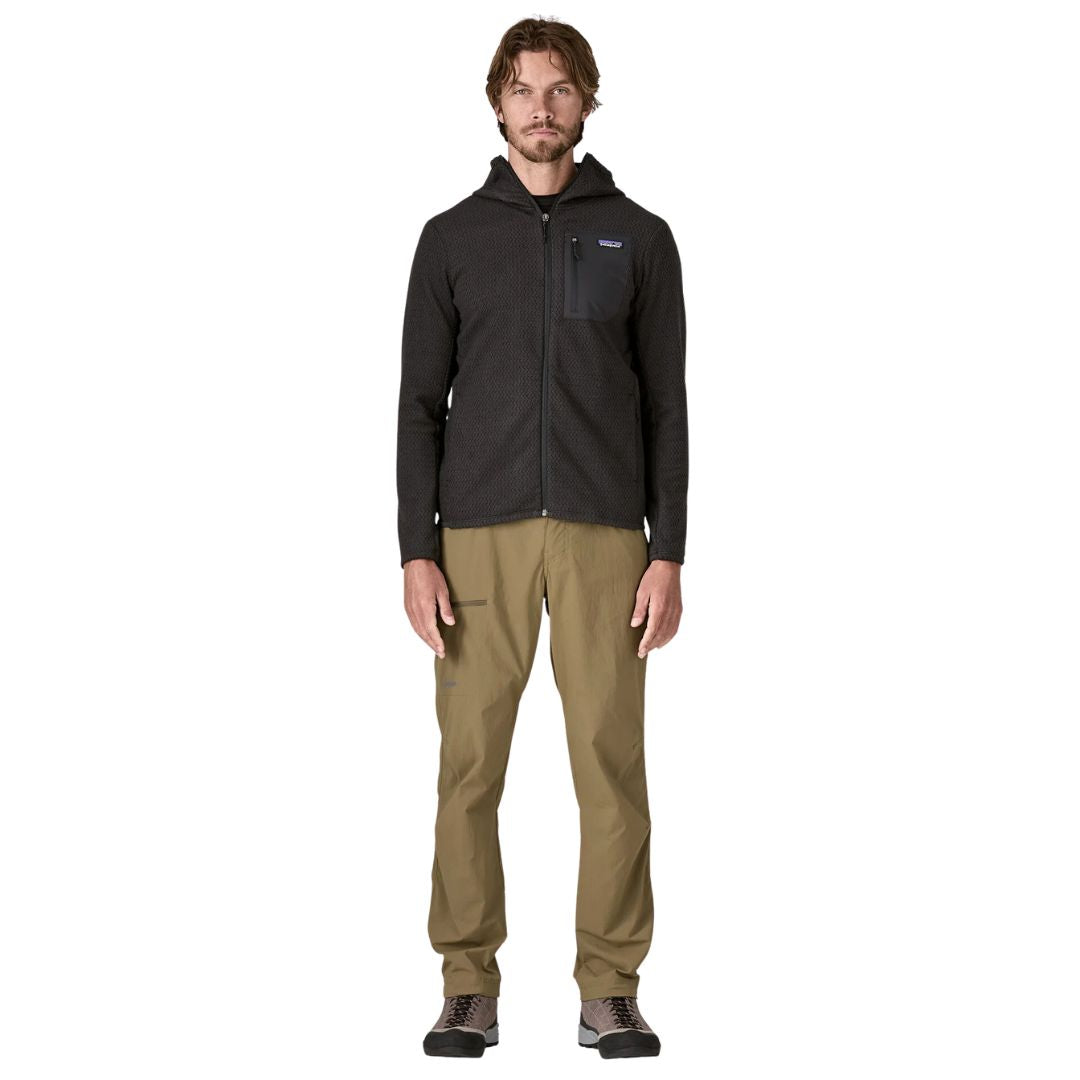 Patagonia Men's R1 Air Full-Zip Hoody en color negro, vista frontal completa con modelo, mostrando cremallera completa, capucha, bolsillo con cremallera en el pecho izquierdo con panel liso y etiqueta Patagonia visible.