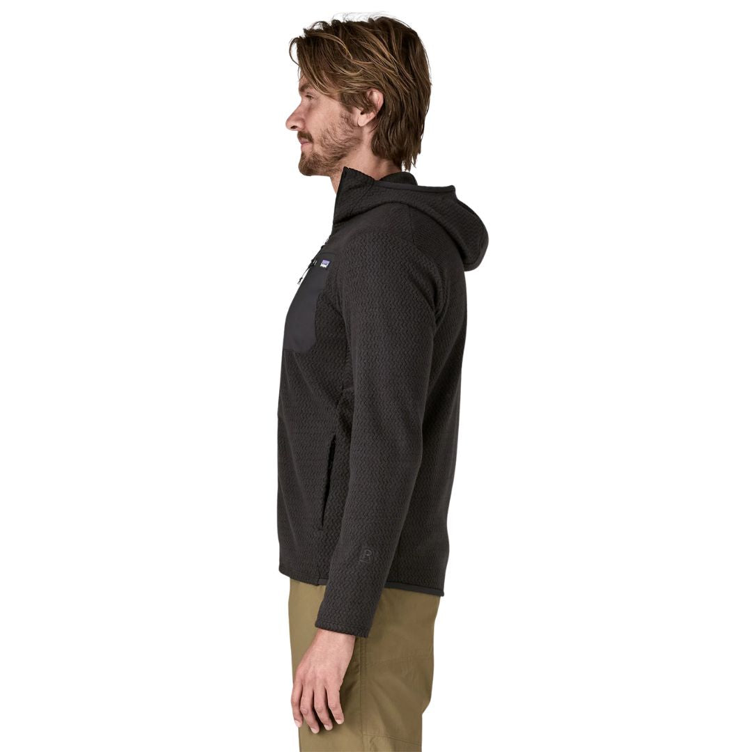 Patagonia Men's R1 Air Full-Zip Hoody en color negro, vista lateral, con capucha ceñida, tejido jacquard en zigzag, bolsillos delanteros con cremalleras minimalistas y logo R1 en el bajo de la manga.