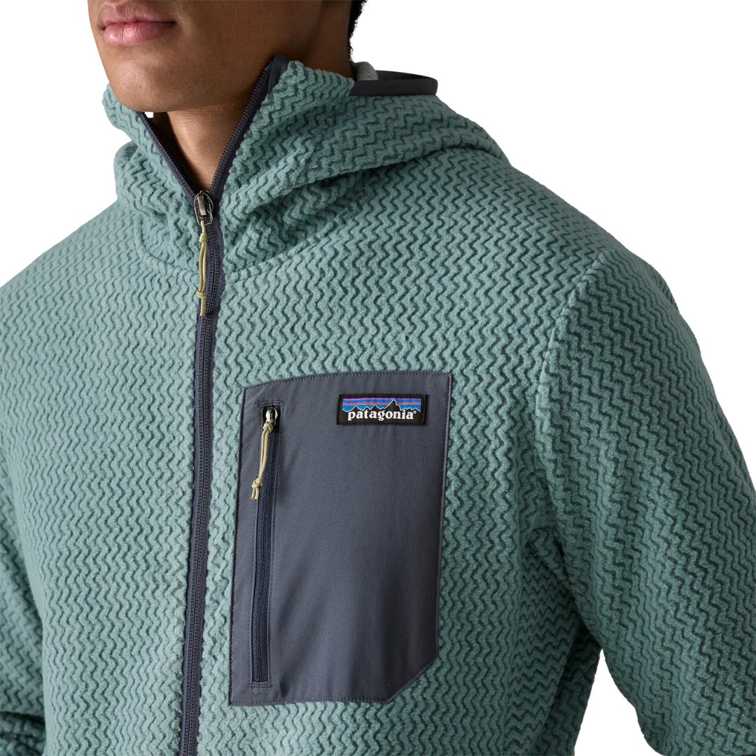 Patagonia Men's R1 Air Full-Zip Hoody, detalle del bolsillo pectoral izquierdo con panel en tejido liso, cremallera con tirador, etiqueta Patagonia y capucha ceñida con ribete interior contrastado.