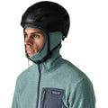 Patagonia Men's R1 Air Full-Zip Hoody con capucha slim-fit colocada bajo casco de esquí o escalada, demostrando la compatibilidad de la capucha ceñida con equipamiento de protección y tejido jacquard en zigzag visible.