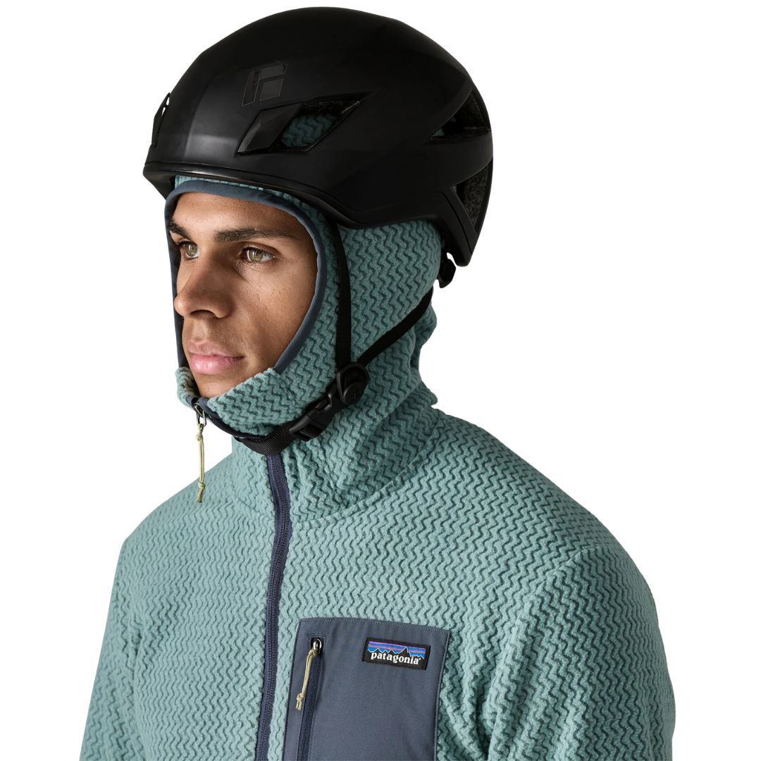 Patagonia Men's R1 Air Full-Zip Hoody con capucha slim-fit colocada bajo casco de esquí o escalada, demostrando la compatibilidad de la capucha ceñida con equipamiento de protección y tejido jacquard en zigzag visible.