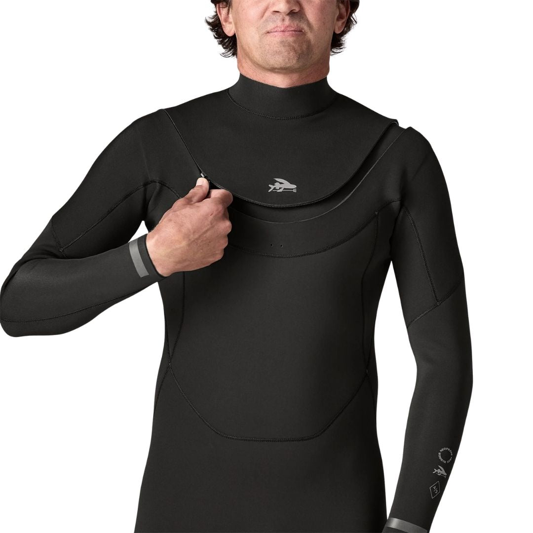 Modelo abriendo la cremallera en U del traje de surf Patagonia Regulator 4/3 en negro a la altura del pecho, con el logotipo del pez volador junto al cierre.