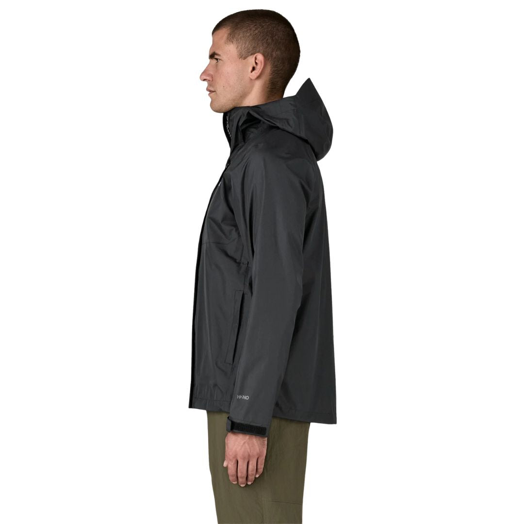 Patagonia Torrentshell 3L color negro, vista lateral en modelo: capucha guardada, bolsillo calientamanos ribeteado, cierre de velcro en puño y logotipo H2No®.