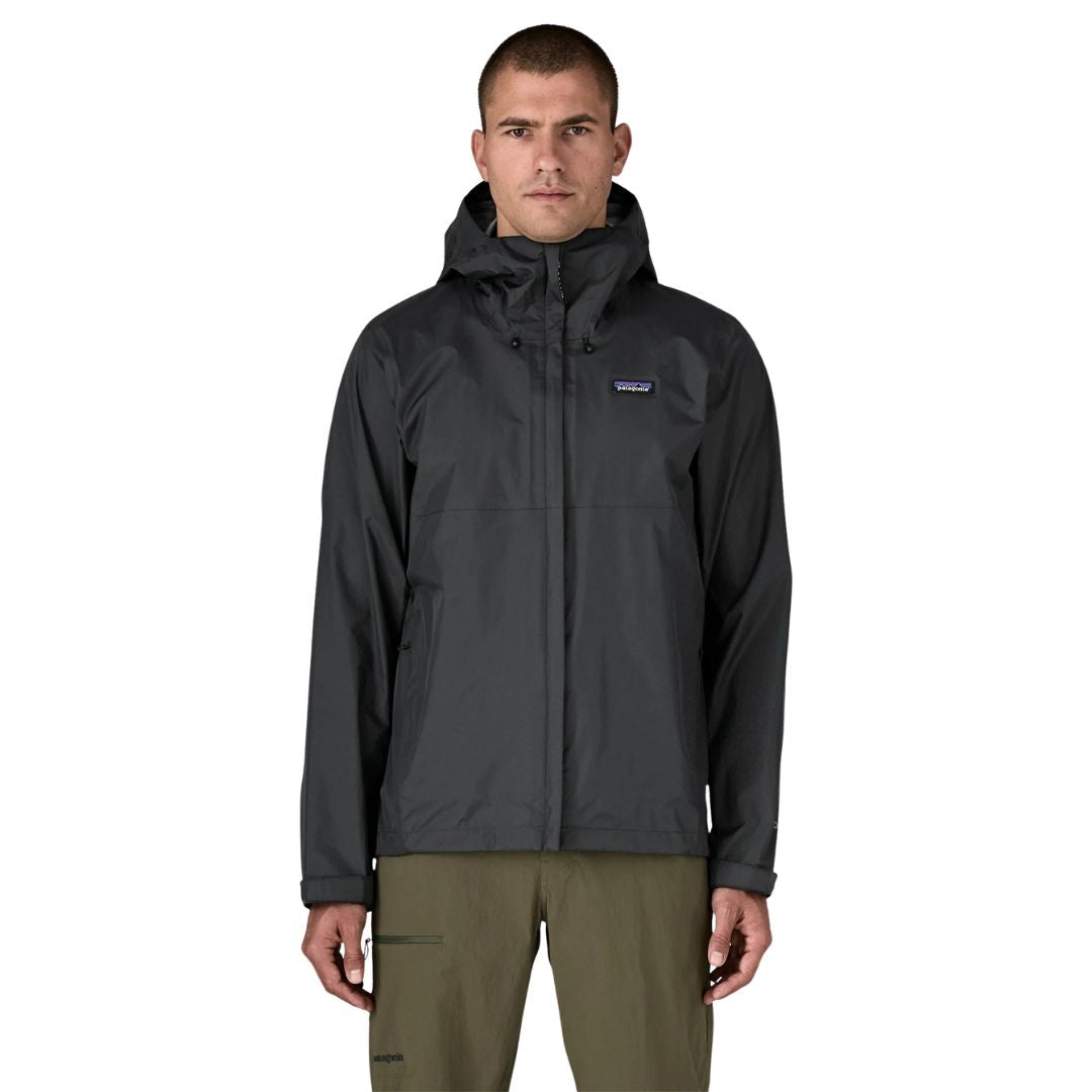 Patagonia Torrentshell 3L color negro, vista frontal en modelo: capucha guardada, cremallera central con solapa antiintemperie, bolsillos calientamanos y parche logo P-6.