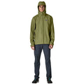 Patagonia Torrentshell 3L color Caper Green, cuerpo completo en modelo con capucha puesta, cremallera central antiintemperie, parche logo P-6 y regular fit.