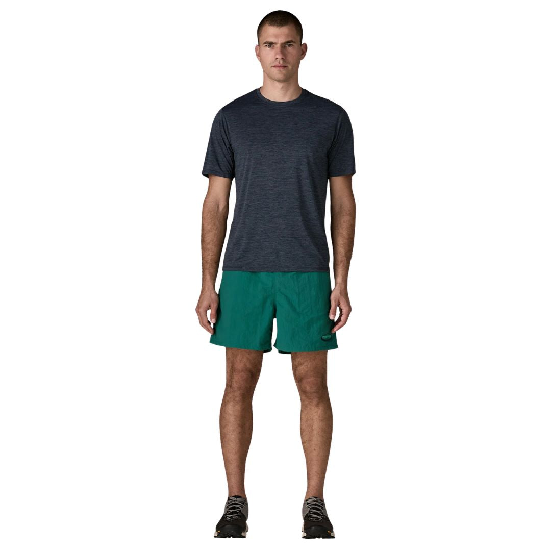 Patagonia Baggies Shorts 5" 95 Oval Logo gem green, vista frontal completa con modelo combinados con camiseta técnica azul marino y zapatillas de trail, en color verde esmeralda.