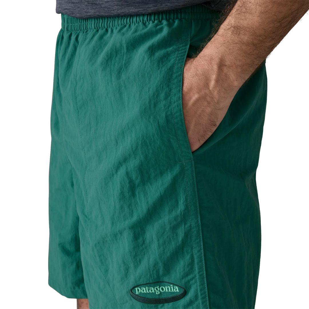 Patagonia Baggies Shorts 5" 95 Oval Logo gem green, detalle del bolsillo lateral vertical con mano del modelo, cinturilla elástica y logo oval vintage en nailon reciclado verde esmeralda.