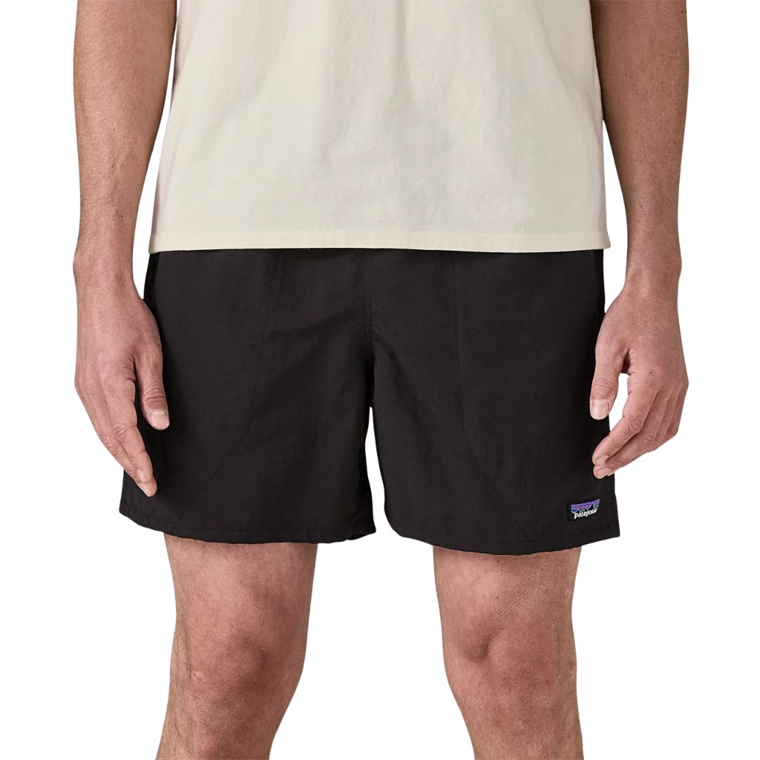 Patagonia Baggies Shorts 5" black on black, vista frontal con modelo, mostrando corte relaxed fit, bolsillos laterales verticales y etiqueta Patagonia en nailon NetPlus reciclado negro.