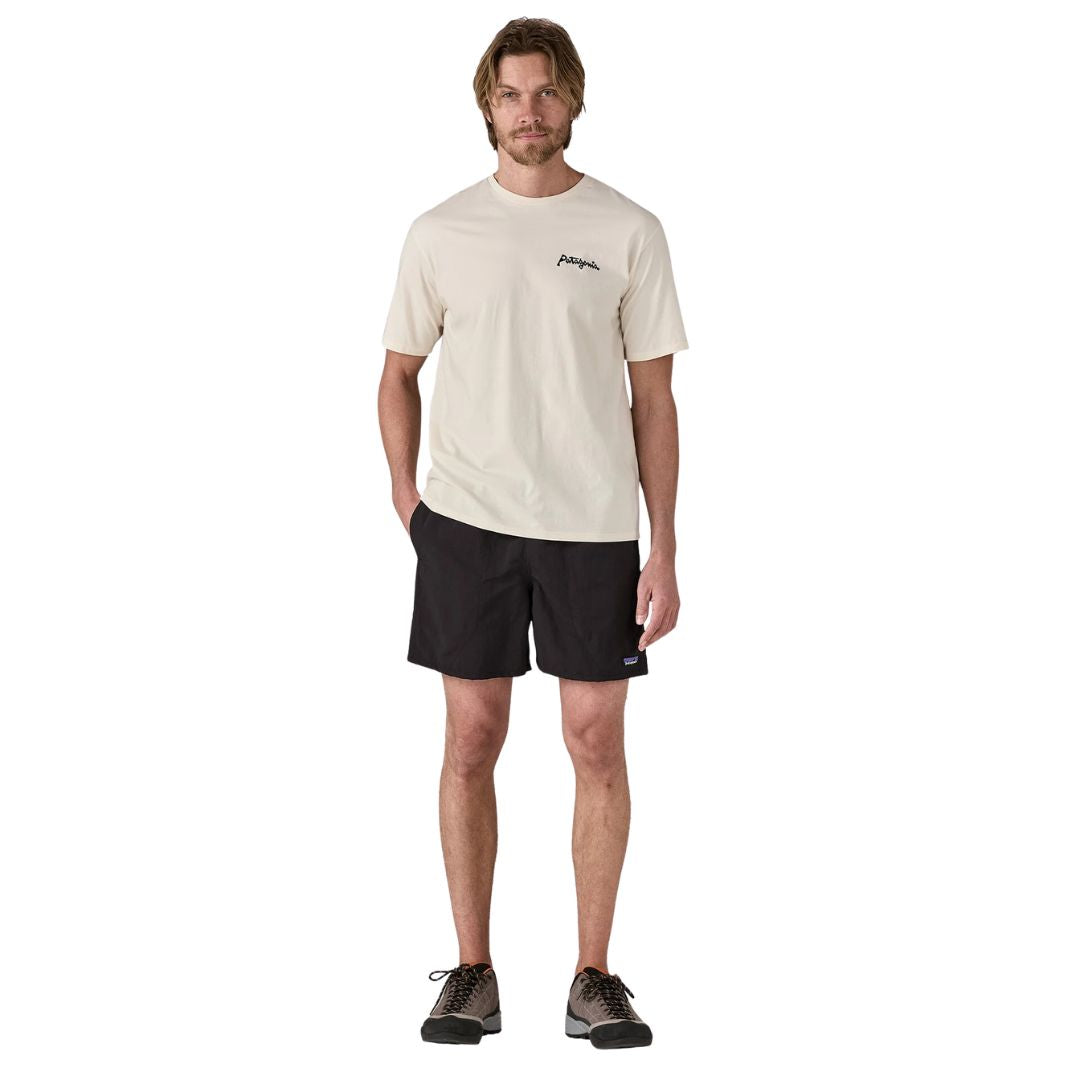 Patagonia Baggies Shorts 5" black on black, vista frontal completa con modelo combinados con camiseta Patagonia crema y zapatillas de trail, mostrando el corte relaxed fit y la cinturilla elástica negra.