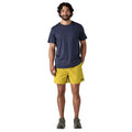 Modelo vistiendo los Patagonia M's Baggies Shorts 5 pulgadas en color amarillo, combinados con camiseta azul marino, mostrando estilo casual y funcional.