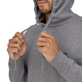 Detalle de la capucha y el cordón ajustable de la sudadera Patagonia P-6 Label Uprisal Hoody en gris Gravel Heather, sobre modelo ajustando los cordones con ambas manos.