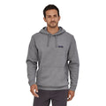 Sudadera con capucha Patagonia P-6 Label Uprisal Hoody en gris Gravel Heather, vista frontal sobre modelo, con la etiqueta Patagonia bordada en el pecho y bolsillo canguro.