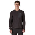 Patagonia M's R1 Air Crew en color negro Black — vista frontal sobre modelo, con tejido jacquard en zigzag de poliéster reciclado y bolsillo con cremallera en el pecho izquierdo en tejido liso negro con etiqueta Patagonia.