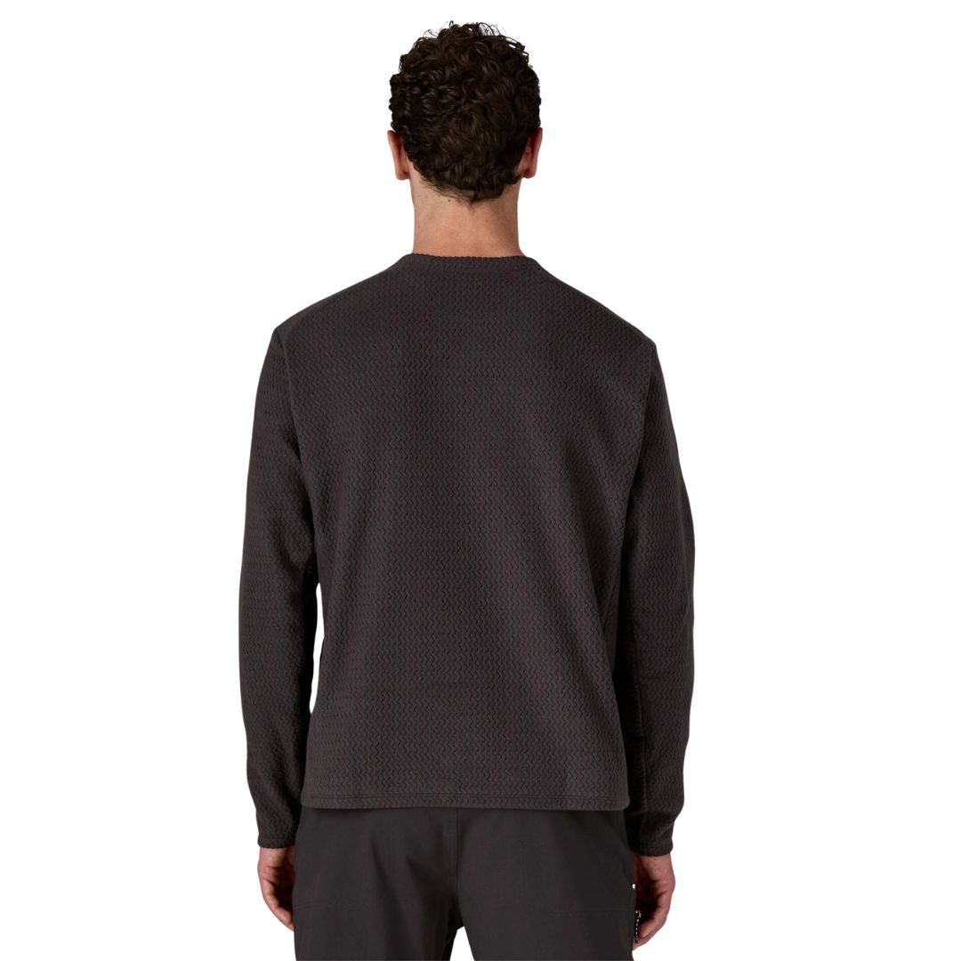 Patagonia M's R1 Air Crew en color negro Black — vista trasera sobre modelo, mostrando el tejido jacquard en zigzag del forro polar técnico reciclado y el ribete tejido de secado rápido en los puños.