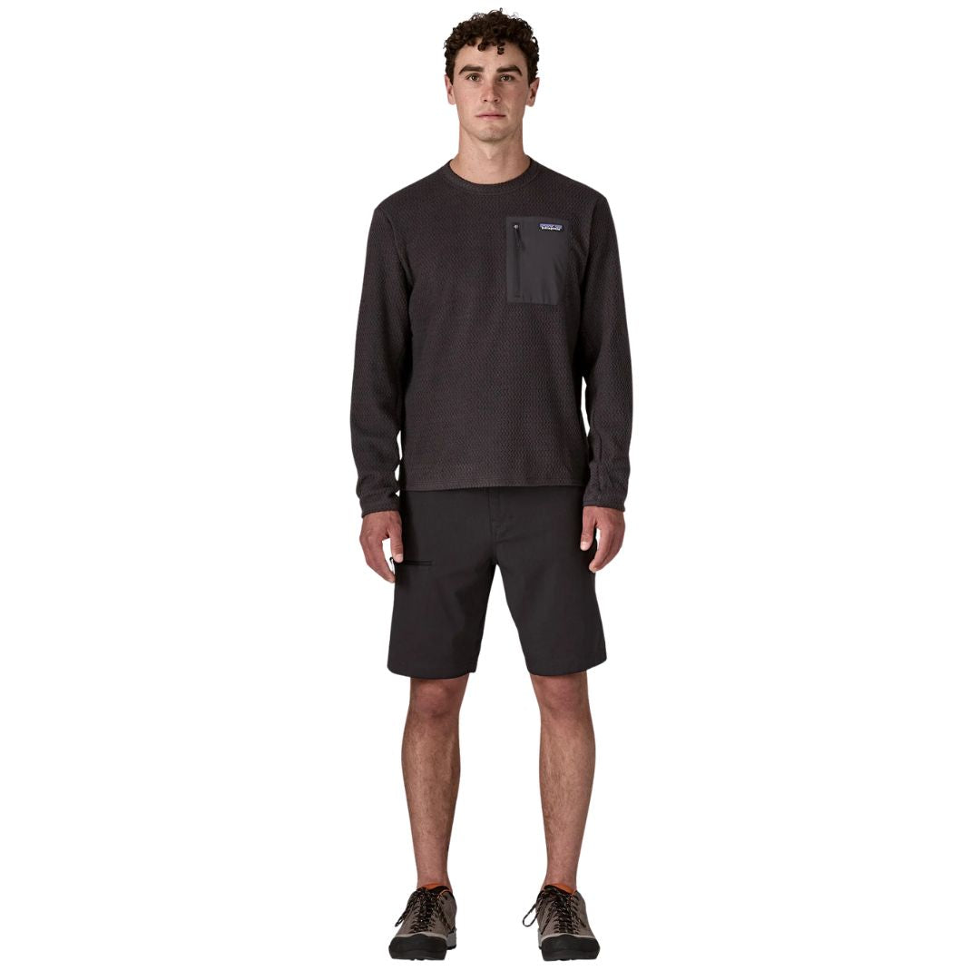 Patagonia M's R1 Air Crew en color negro Black — vista frontal completa sobre modelo con pantalón corto y zapatillas de montaña, mostrando el largo y el corte recto del forro polar técnico reciclado.