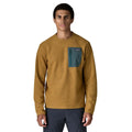 Patagonia M's R1 Air Crew en color marrón Bobcat Brown — vista frontal sobre modelo, con tejido jacquard en zigzag de poliéster reciclado y bolsillo con cremallera en el pecho izquierdo en contraste verde azulado con etiqueta Patagonia.
