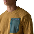 Detalle del bolsillo con cremallera del Patagonia M's R1 Air Crew Bobcat Brown — primer plano del bolsillo en tejido verde azulado con etiqueta Patagonia y textura jacquard en zigzag del forro polar técnico reciclado.