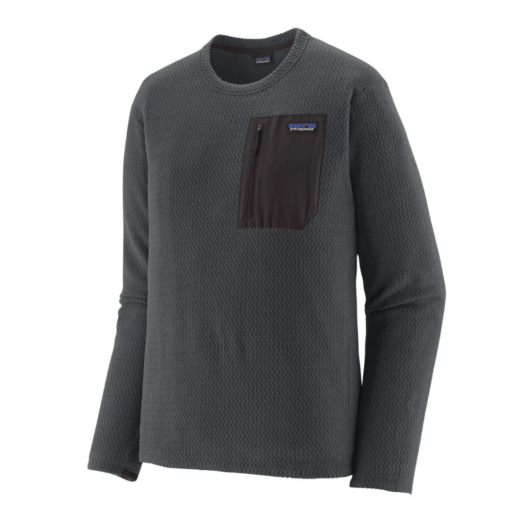 Jersey Patagonia R1 Air Crew en color Smolder Blue, vista de producto en plano tres cuartos sobre fondo blanco, mostrando el bolsillo con cremallera y el logo bordado en la manga.