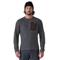 Jersey Patagonia R1 Air Crew en color Smolder Blue, primer plano frontal sobre modelo, con detalle del bolsillo con cremallera en el pecho y etiqueta Patagonia visible.