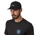 Patagonia P-6 Label Trad Cap negra gorra estilo béisbol de algodón orgánico con logo frontal, corona baja sin estructura y visera curva NetPlus reciclada vista frontal con modelo.