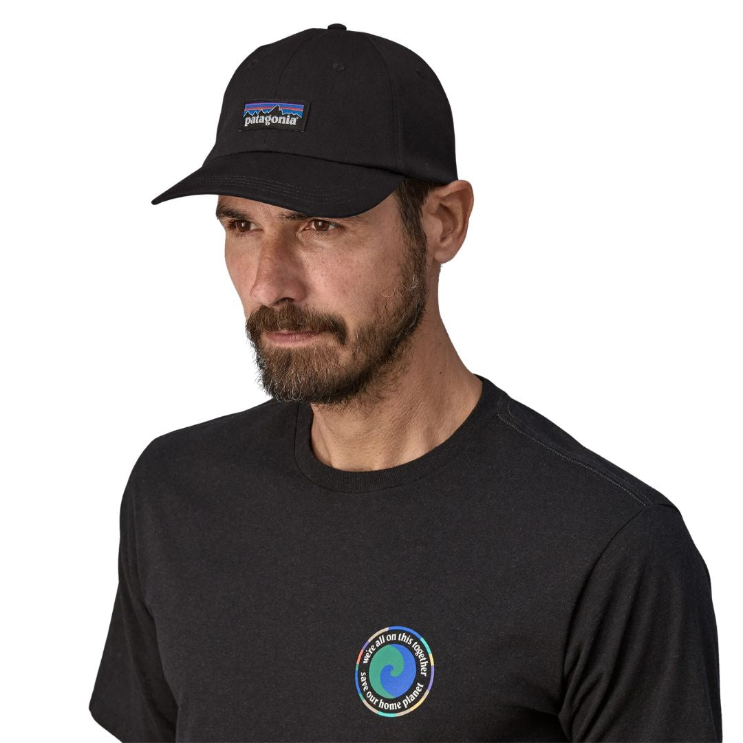 Patagonia P-6 Label Trad Cap negra gorra estilo béisbol de algodón orgánico con logo frontal, corona baja sin estructura y visera curva NetPlus reciclada vista frontal con modelo.