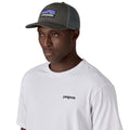 Gorra trucker Patagonia P-6 Logo en color gris (Forge Grey), modelo con la gorra puesta de perfil mostrando el parche P-6 bordado y la rejilla de malla trasera.