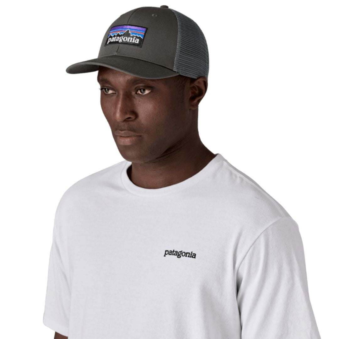 Gorra trucker Patagonia P-6 Logo en color gris (Forge Grey), modelo con la gorra puesta de perfil mostrando el parche P-6 bordado y la rejilla de malla trasera.