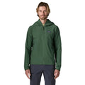 Patagonia R1 TechFace Hoody verde canopy, chaqueta técnica con capucha para hombre. Vista frontal de cuerpo entero con cremallera subida y bolsillo de pecho con logo Patagonia visible.