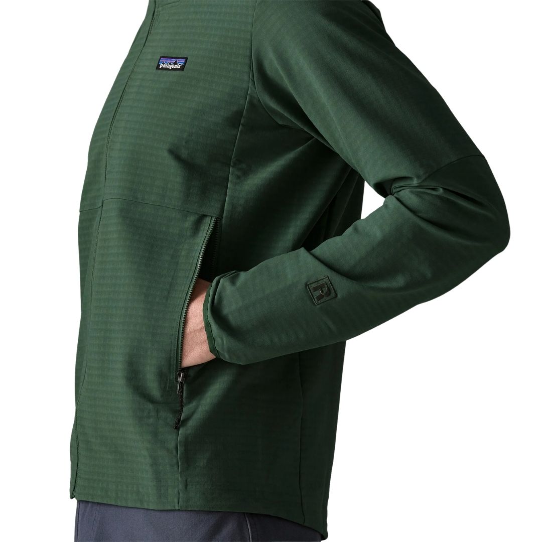 Patagonia R1 TechFace Hoody verde canopy, chaqueta técnica con capucha para hombre. Detalle lateral con la mano en el bolsillo con cremallera y el logo 'R' bordado en el puño de la manga.