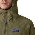 Patagonia R1® TechFace Hoody en uso real con humedad en la cara exterior: acabado DWR sin PFAS activo, capucha con visera y cremallera con tirador naranja.