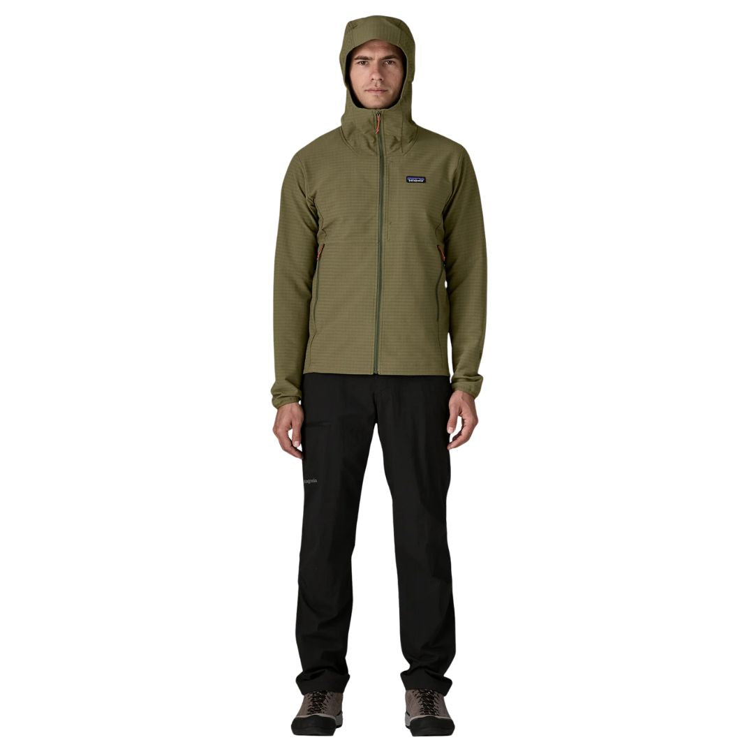 Patagonia R1® TechFace Hoody, cuerpo completo en modelo con capucha puesta: cremallera completa, slim fit articulado y bolsillos calientamanos con zipper naranja.