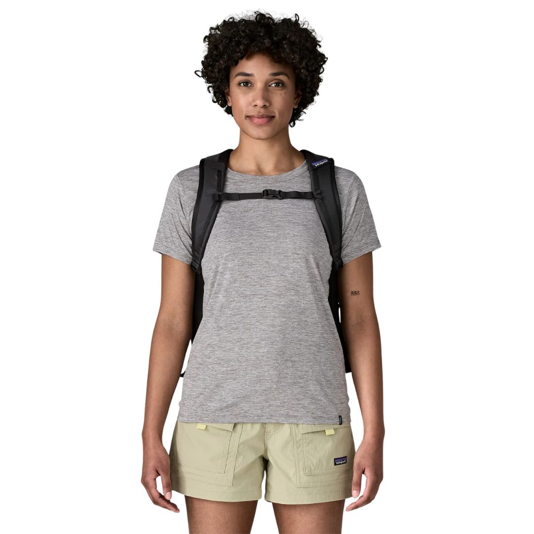 Patagonia Refugio Daypack 26L en color negro, vista frontal con modelo, mostrando correas acolchadas, correa esternal ajustable con cierre de hebilla y perfil compacto de 26 litros.
