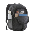 Patagonia Refugio Daypack 26L en color negro, compartimento frontal abierto con organización interna mostrando cuadernos, móvil y accesorios, bolsillo lateral de malla elástica con botella de agua y luz de bicicleta enganchada en la base.