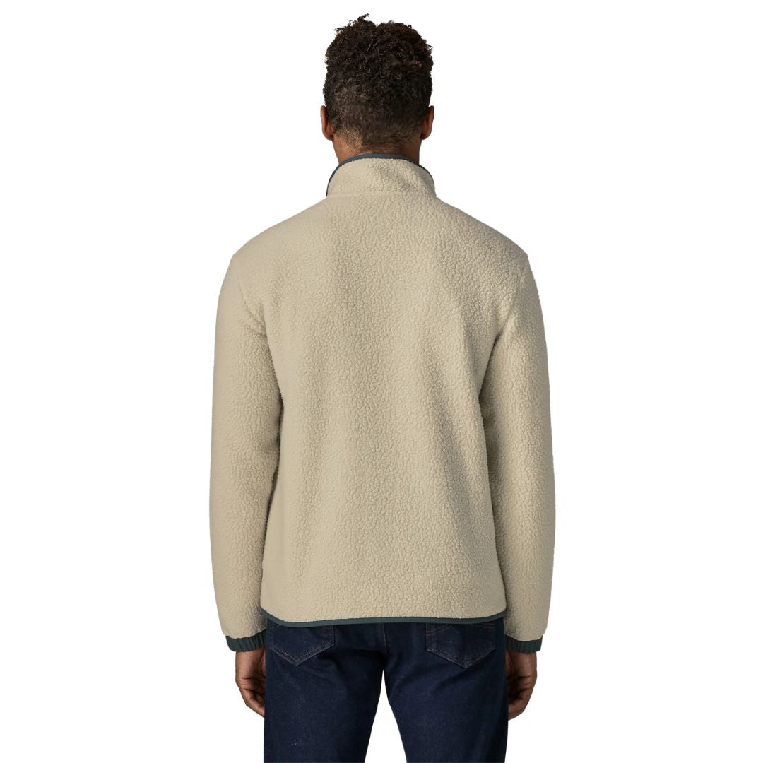 Espalda de la chaqueta polar Patagonia Retro Pile Fleece Patch Jacket en color beige Pelican: borreguillo de doble cara continuo, cuello alto y bajo con ribete azul pizarra, sobre vaqueros oscuros.