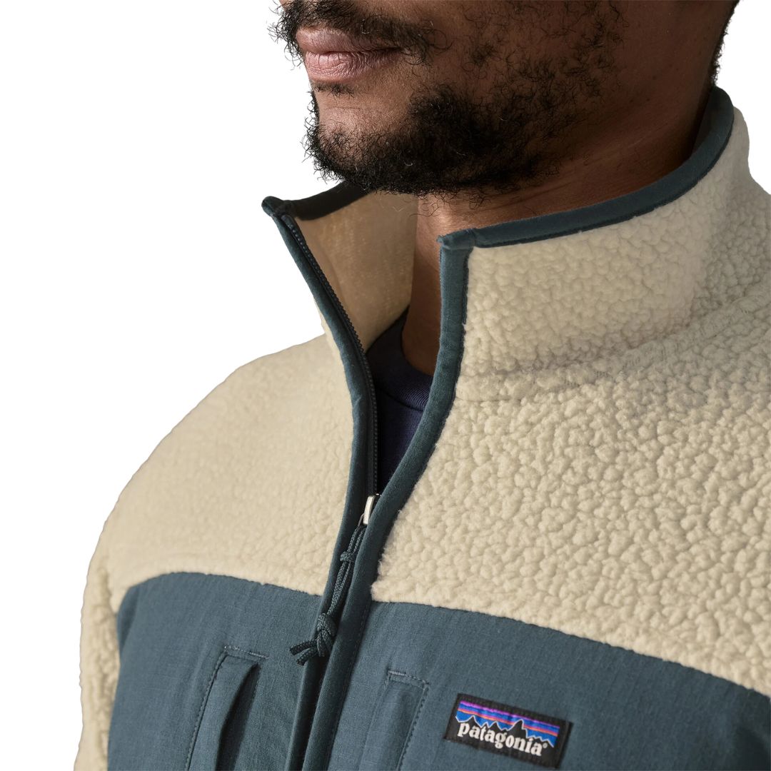 Detalle del cuello de la Patagonia Retro Pile Fleece Patch Jacket en color beige Pelican: cuello alto de borreguillo con ribete azul pizarra, cremallera con tirador de cordón y parche Patagonia.