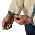 Detalle del puño de la Patagonia Retro Pile Fleece Patch Jacket en color beige Pelican: borreguillo de doble cara y puño elástico de ripstop en azul pizarra ajustado con la mano.