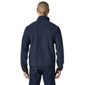 Espalda de la chaqueta polar Patagonia Retro Pile Fleece Jacket en color azul marino New Navy: borreguillo de doble cara continuo, cuello alto y bajo con ribete negro, sobre vaqueros oscuros.