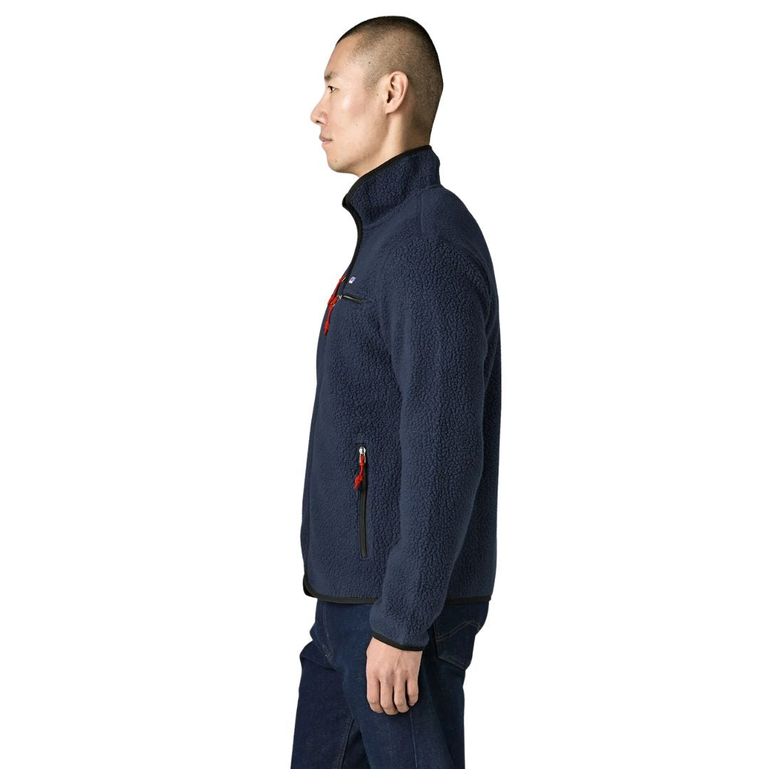 Perfil de la chaqueta polar Patagonia Retro Pile Fleece Jacket en color azul marino New Navy: cuello alto con ribete negro, tiradores de cinta rojos y bolsillo calientamanos con cremallera.