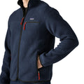 Detalle de la Patagonia Retro Pile Fleece Jacket en color azul marino New Navy: parche Patagonia, bolsillo de pecho con cremallera negra, tiradores rojos y mano en el bolsillo calientamanos.