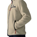 Detalle de la Patagonia Retro Pile Fleece Jacket en color beige Pelican: parche Patagonia, bolsillo de pecho con cremallera azul marino, tiradores rojos y mano en el bolsillo calientamanos.