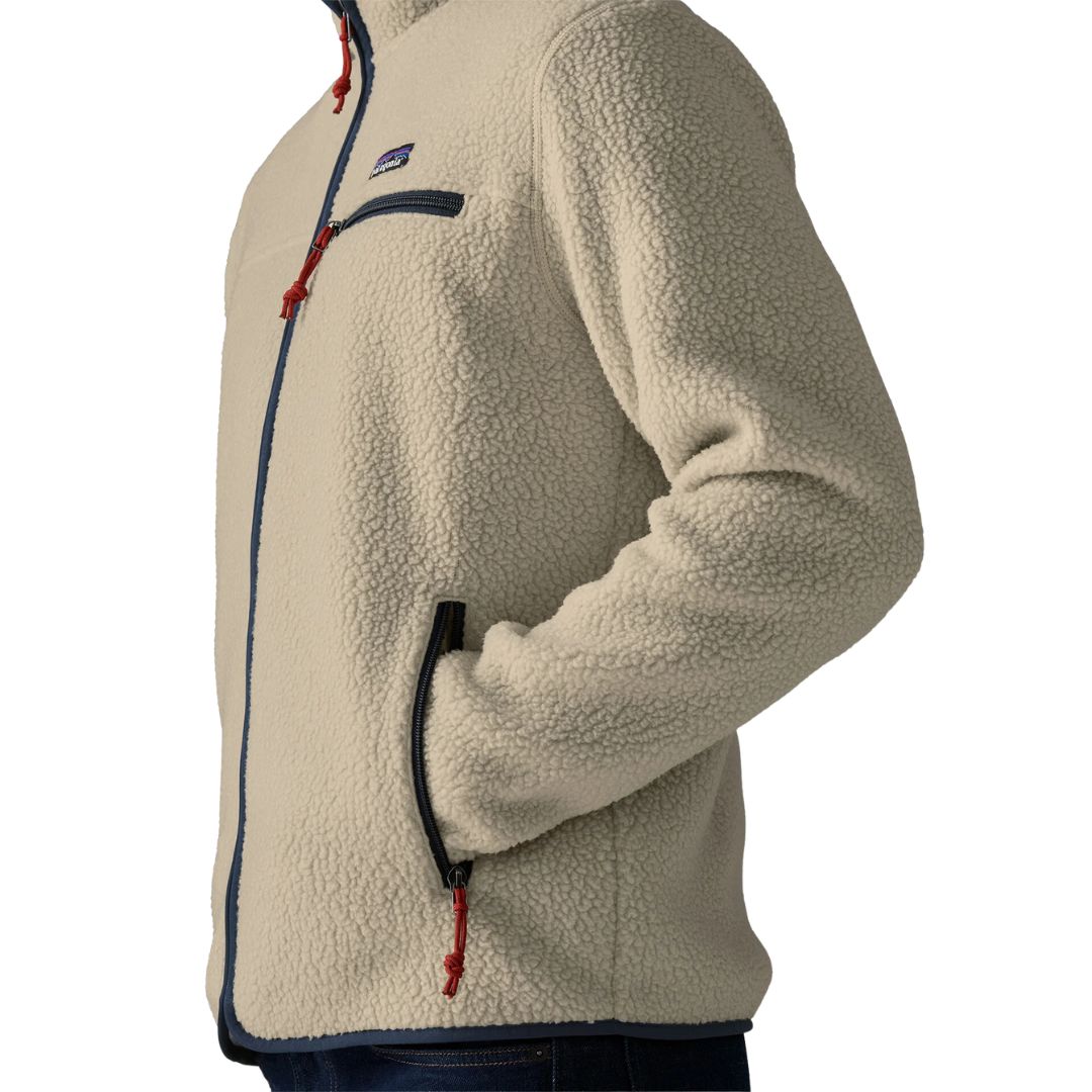 Detalle de la Patagonia Retro Pile Fleece Jacket en color beige Pelican: parche Patagonia, bolsillo de pecho con cremallera azul marino, tiradores rojos y mano en el bolsillo calientamanos.