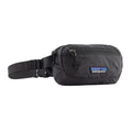 Patagonia Terravia Mini Hip Pack 1L en color negro, vista de producto en tres cuartos sin modelo, mostrando el compartimento principal con cremallera metálica, el bolsillo frontal de seguridad, la etiqueta Patagonia con logo Fitz Roy y la correa de nailon reciclado con ajustador.