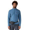 Patagonia Terravia Mini Hip Pack 1L en color negro, vista frontal con modelo llevándola como riñonera en la cintura, mostrando el compartimento principal con cremallera, el bolsillo frontal de seguridad con etiqueta Patagonia y la correa antideslizante ajustable.