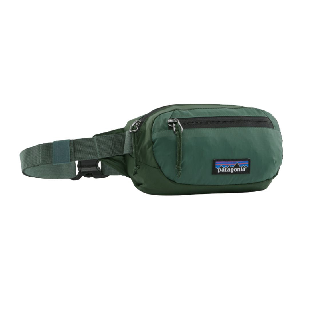 Riñonera Patagonia Terravia Mini Hip Pack en color verde bosque (Canopy Green), vista de perfil con la cremallera cerrada, el bolsillo frontal y el parche Patagonia.
