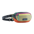 Patagonia Terravia Mini Hip Pack 1L en color patchwork gumtree green, vista frontal de producto en tres cuartos sin modelo, mostrando el diseño multicolor en bloques de verde oliva, amarillo, magenta, naranja y gris oscuro, compartimento principal con cremallera turquesa, bolsillo frontal de seguridad y etiqueta Patagonia con logo Fitz Roy.