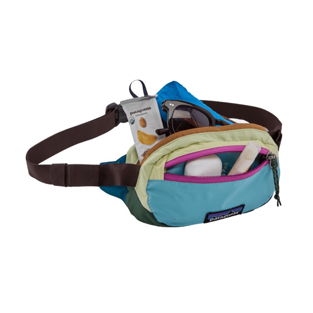 Riñonera Patagonia Terravia Mini Hip Pack en colorway Patchwork Snowmelt Blue, vista de detalle con el bolsillo abierto mostrando gafas de sol, snacks y accesorios en su interior.
